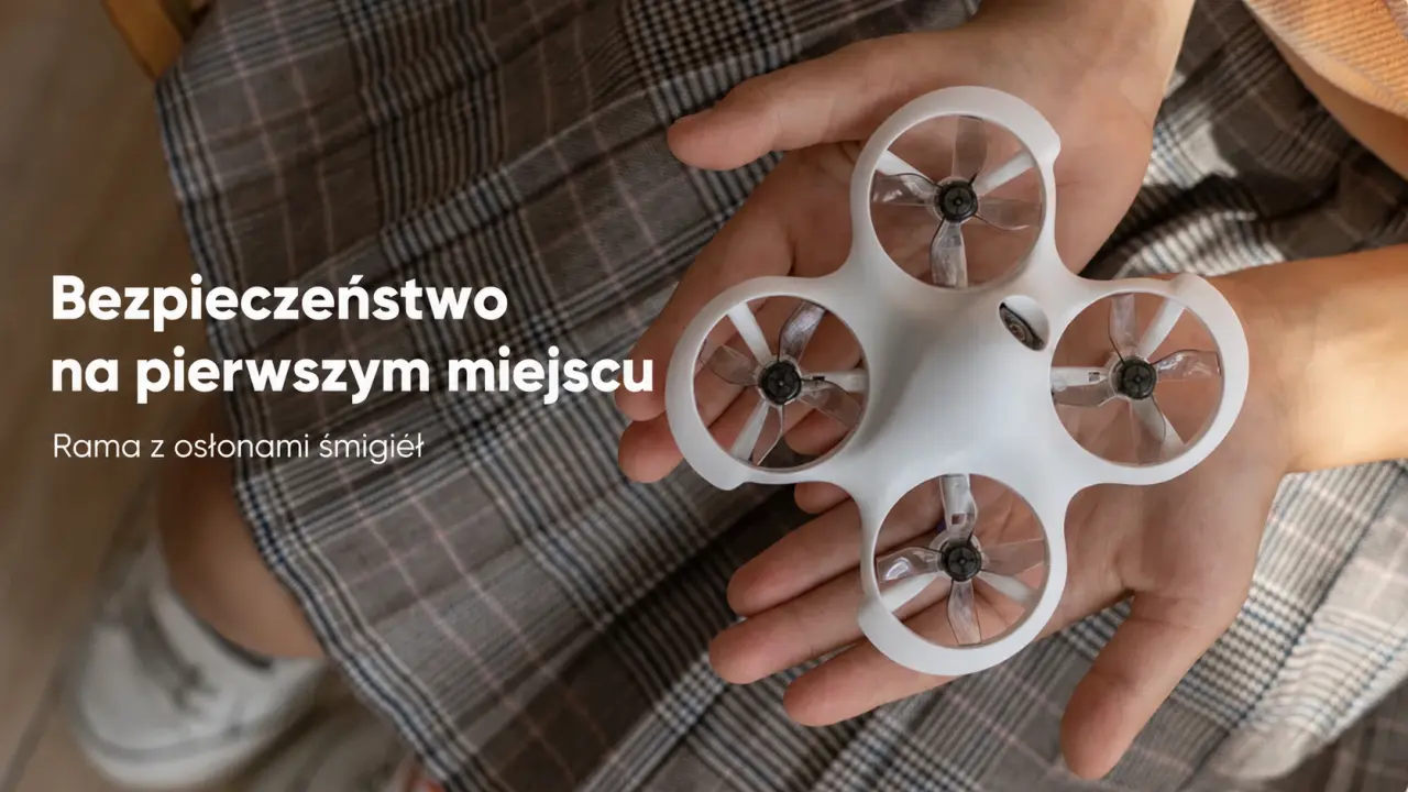 Biały mini dron FPV z osłonami śmigieł trzymany w dłoniach.