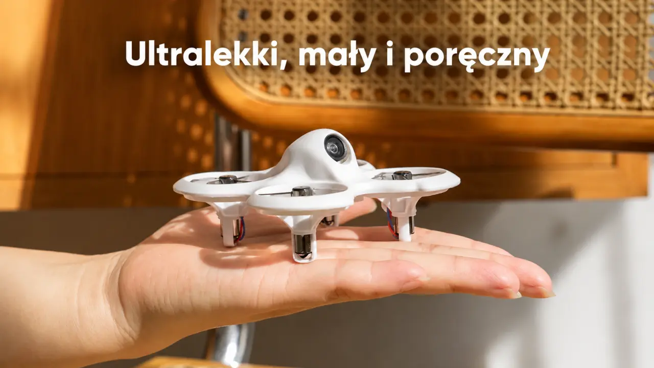 Kompaktowy biały mini dron FPV leżący na otwartej dłoni.