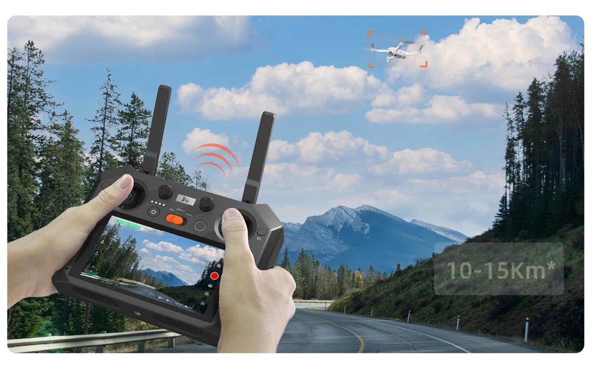 un controlador de un dron fimi con una pantalla en las manos, controlando el dron frente a un paisaje montañoso y una carretera. Se marca un alcance de 10-15 km