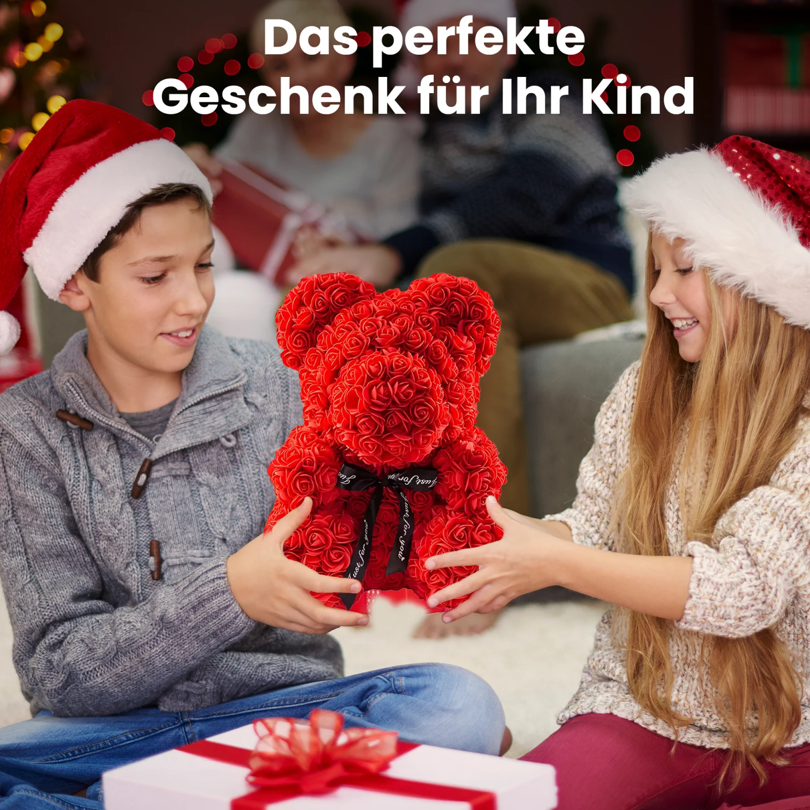 Zwei lächelnde Kinder mit Weihnachtsmannmützen, ein Junge und ein Mädchen, halten einen roten Teddybären mit rosa