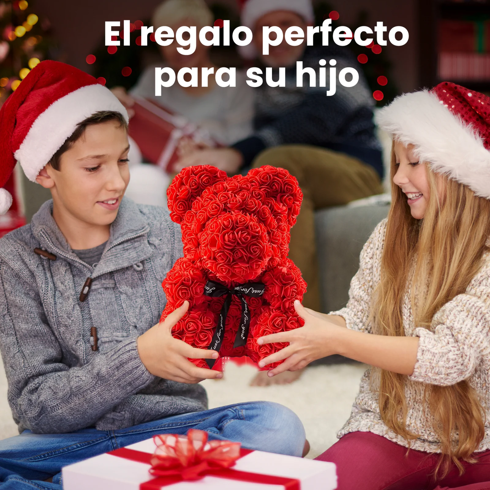 Dos ni&ntilde;os sonrientes con gorros de Pap&aacute; Noel, un ni&ntilde;o y una ni&ntilde;a, sostienen juntos un osito de peluche rojo con rosa.