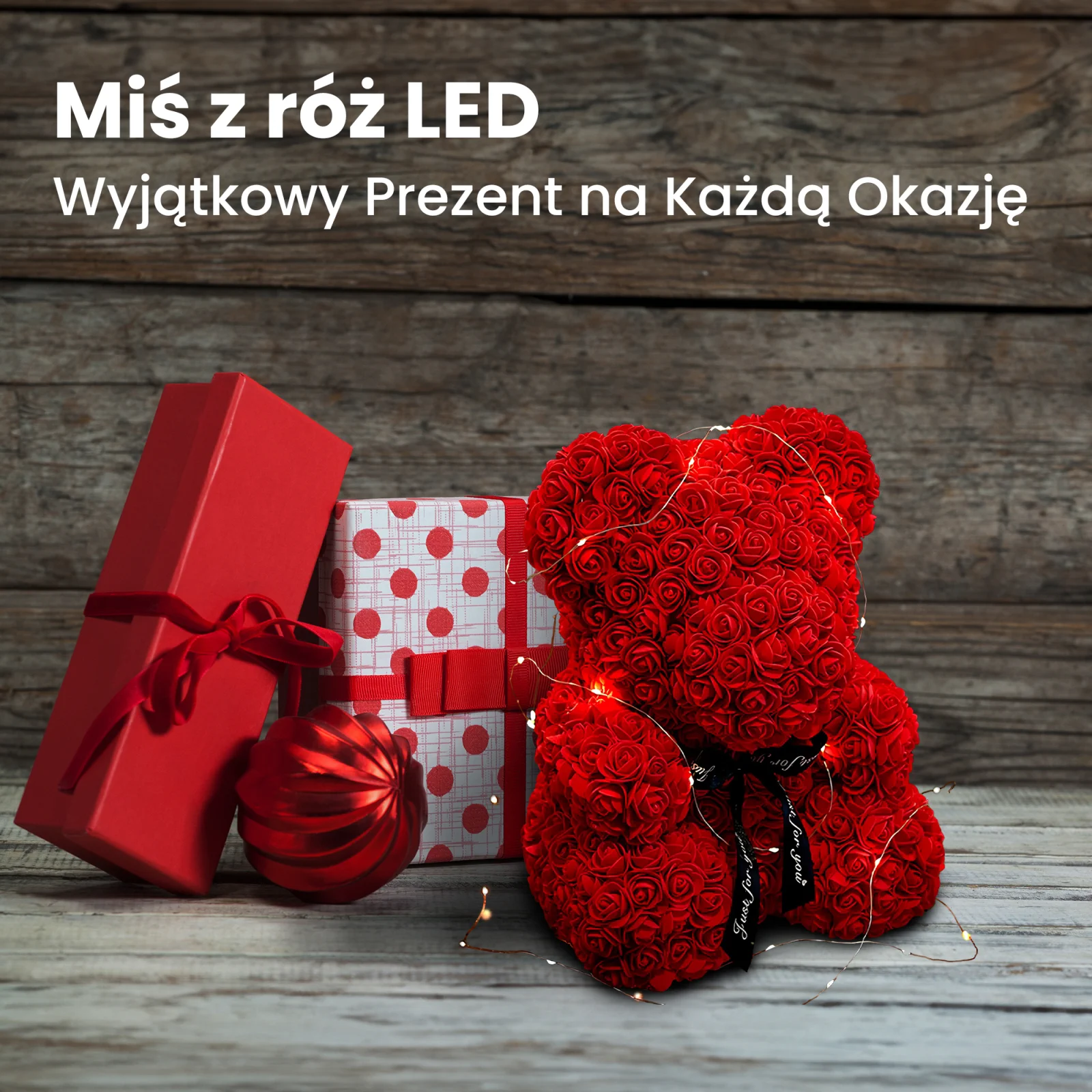 Un osito de peluche con una rosa roja, envuelto en luces LED, junto a dos cajas de regalo y una chuchería.