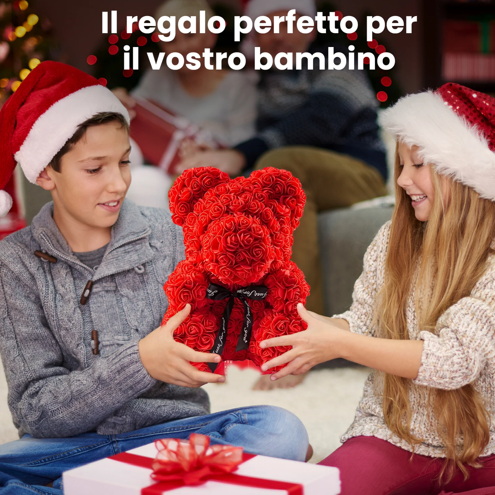 Due bambini sorridenti con cappelli da Babbo Natale, un maschio e una femmina, tengono insieme un orsacchiotto di peluche rosso e rosa.