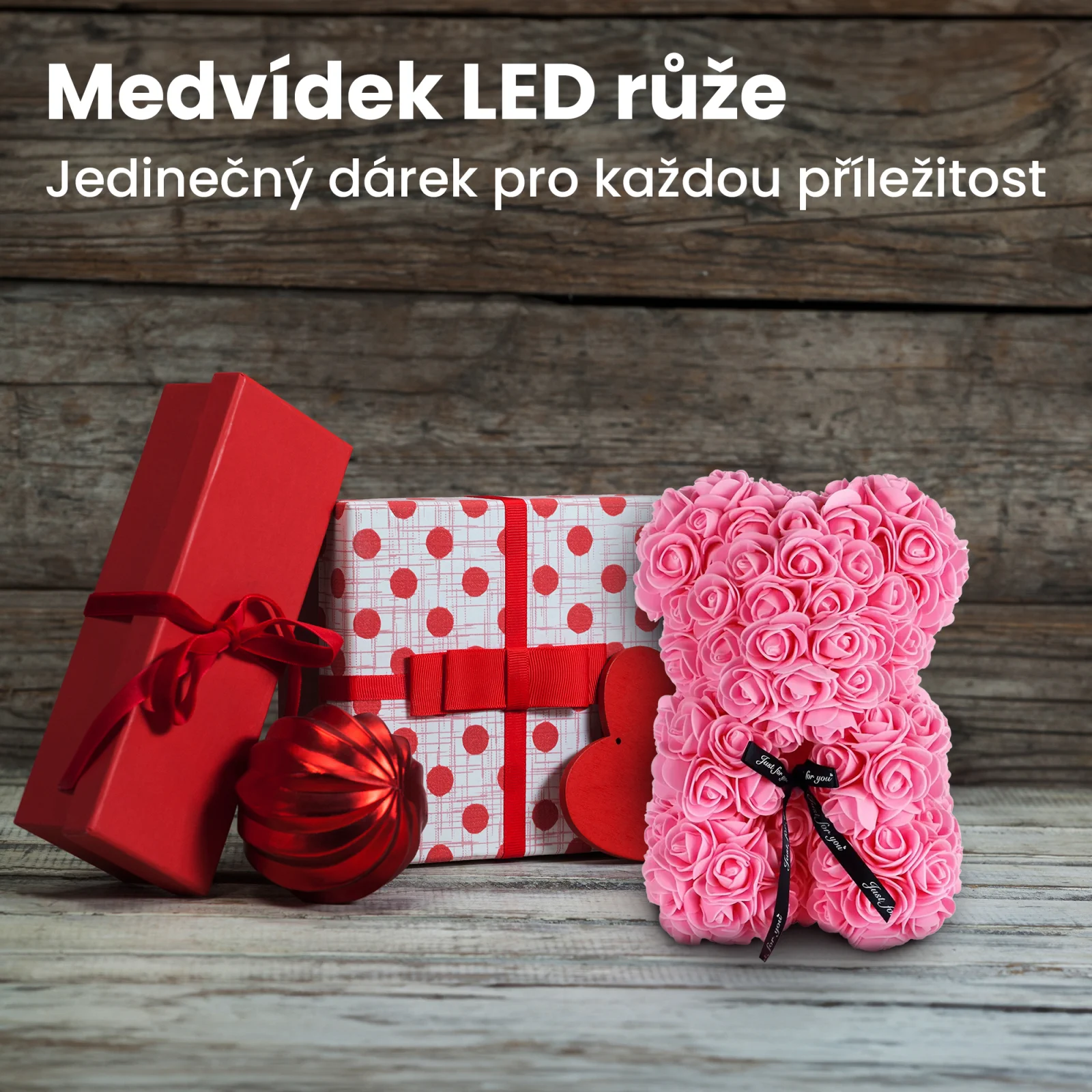 růžový růžový medvídek stojí vedle dvou dárkových krabiček a cetky.