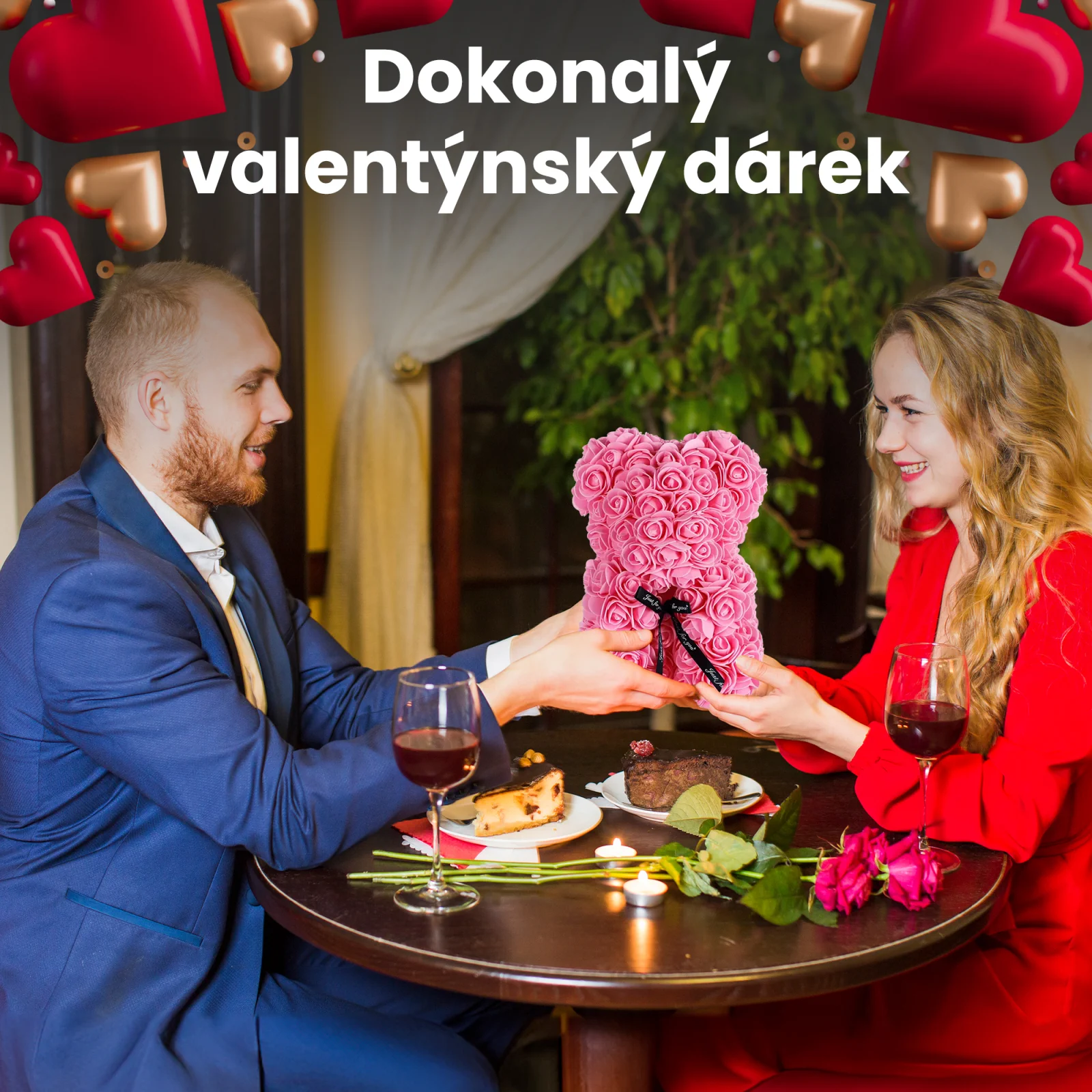 P&aacute;r se usm&iacute;v&aacute;, když sed&iacute; u stolu v restauraci, a muž před&aacute;v&aacute; ženě růžov&eacute;ho medv&iacute;dka s růžovou barvou.
