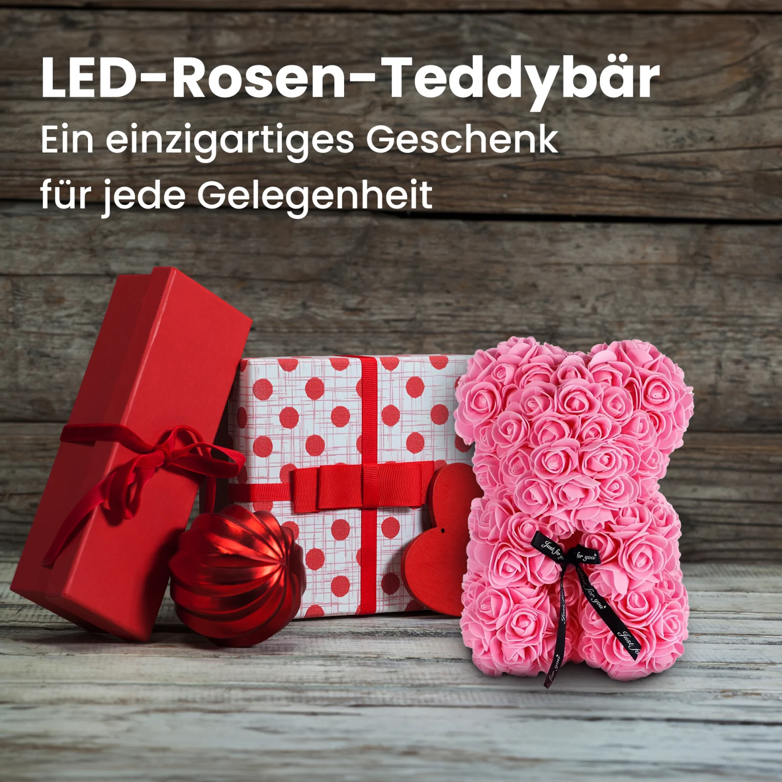 rosa rosa Teddybär steht neben zwei Geschenkschachteln und einer Christbaumkugel