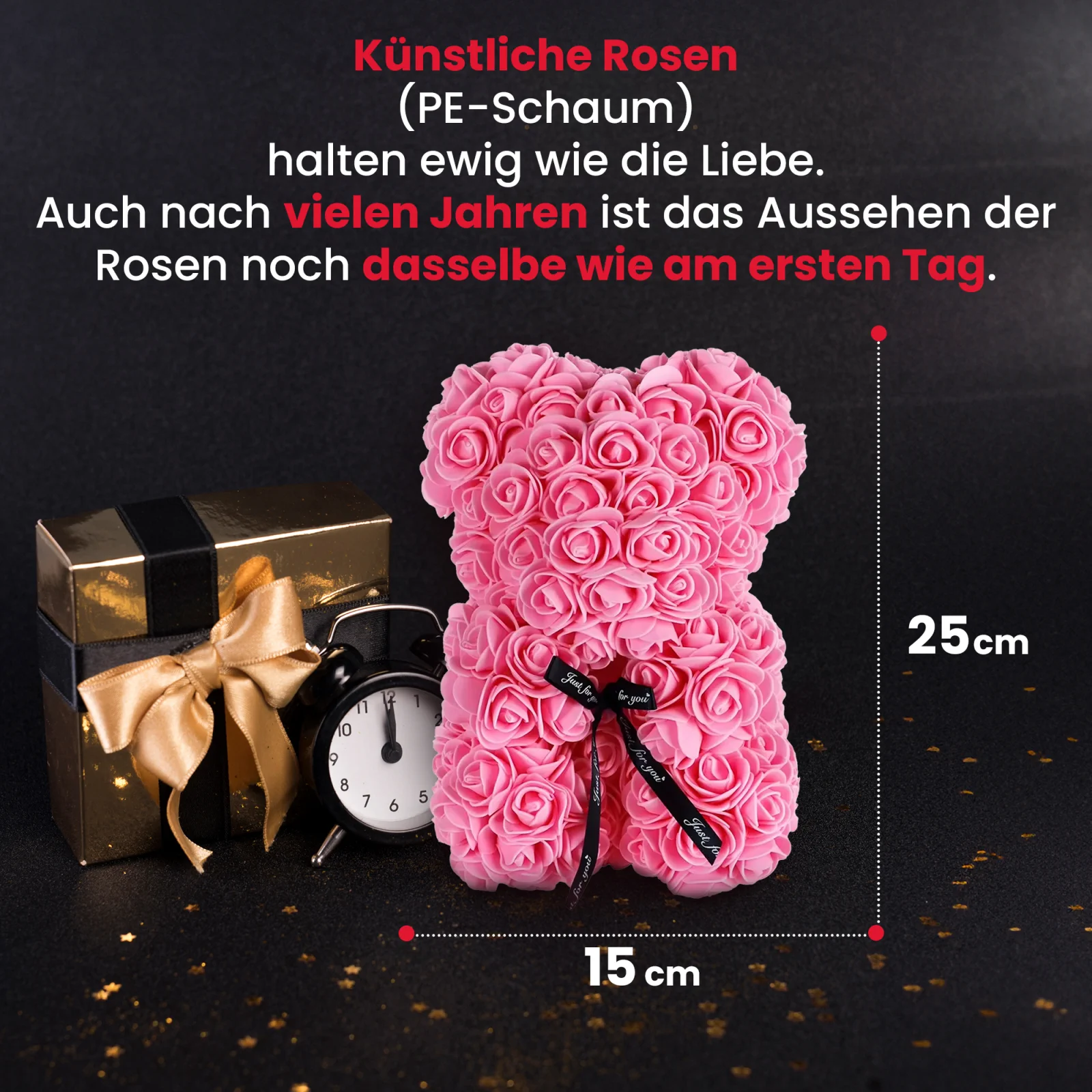 rosa rosa Teddybär steht neben einer goldenen Geschenkbox und einer schwarzen Uhr