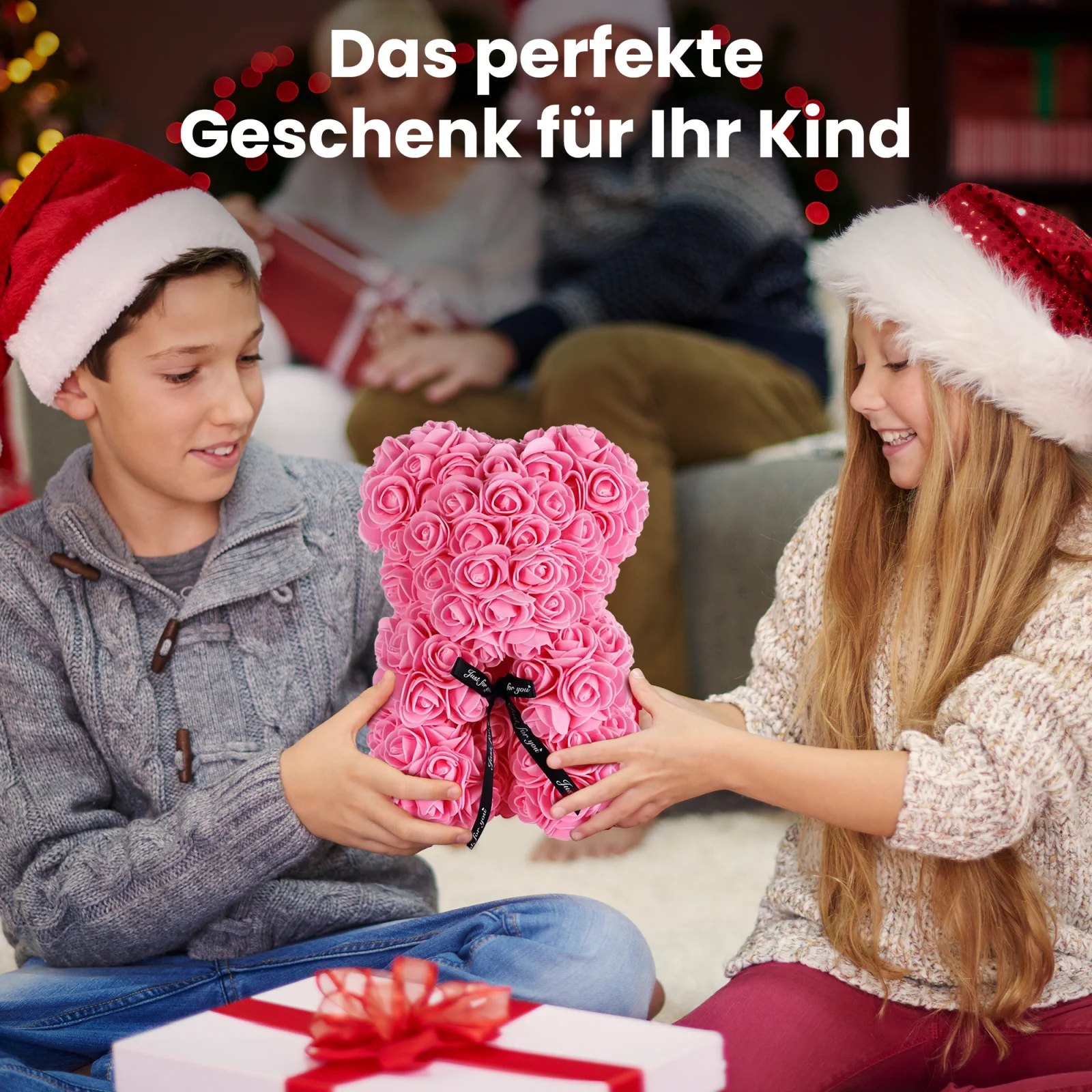 Zwei lächelnde Kinder mit Weihnachtsmannmützen, ein Junge und ein Mädchen, halten einen rosa Teddybär mit rosa
