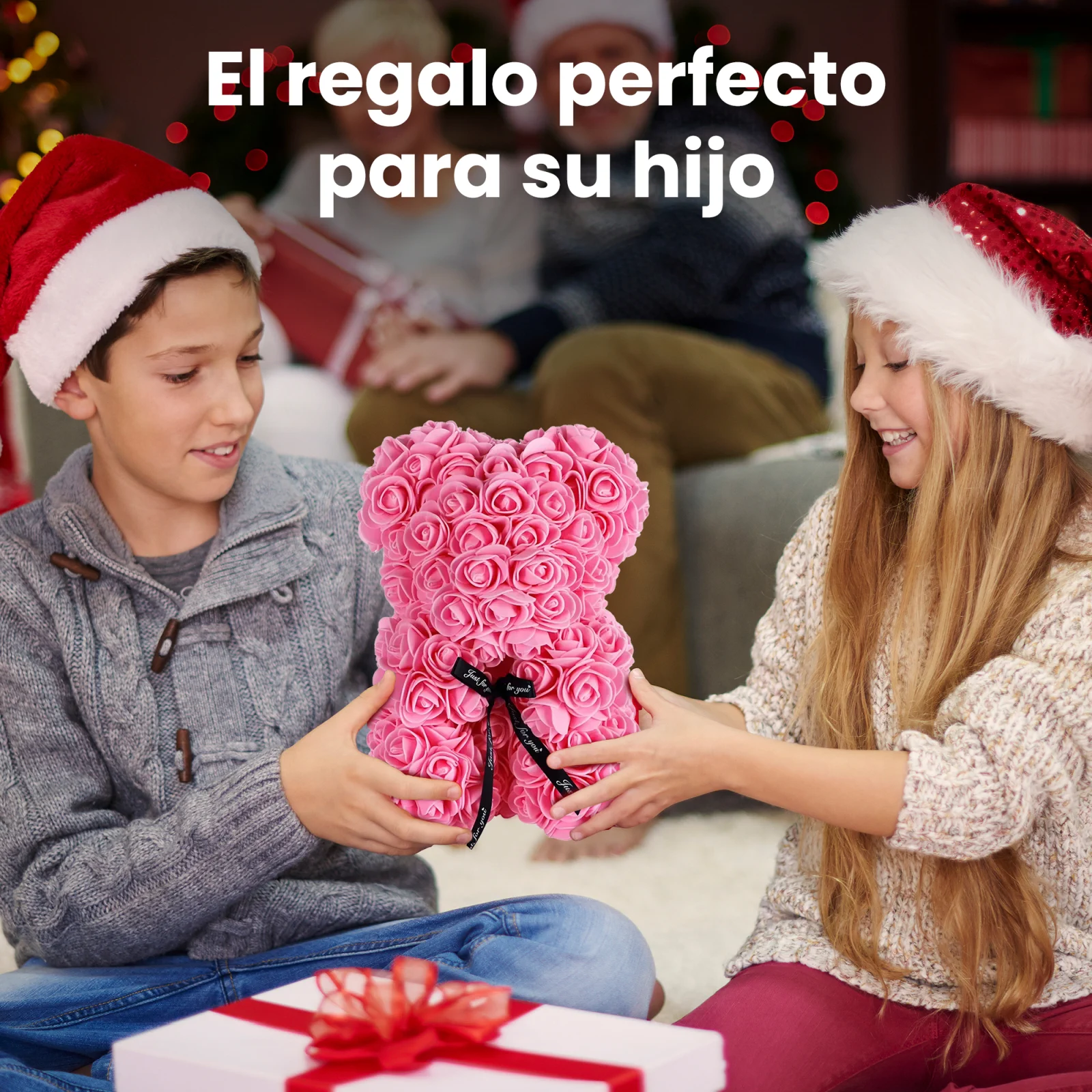 Dos ni&ntilde;os sonrientes con gorros de Pap&aacute; Noel, un ni&ntilde;o y una ni&ntilde;a, sosteniendo juntos un osito de peluche rosa con