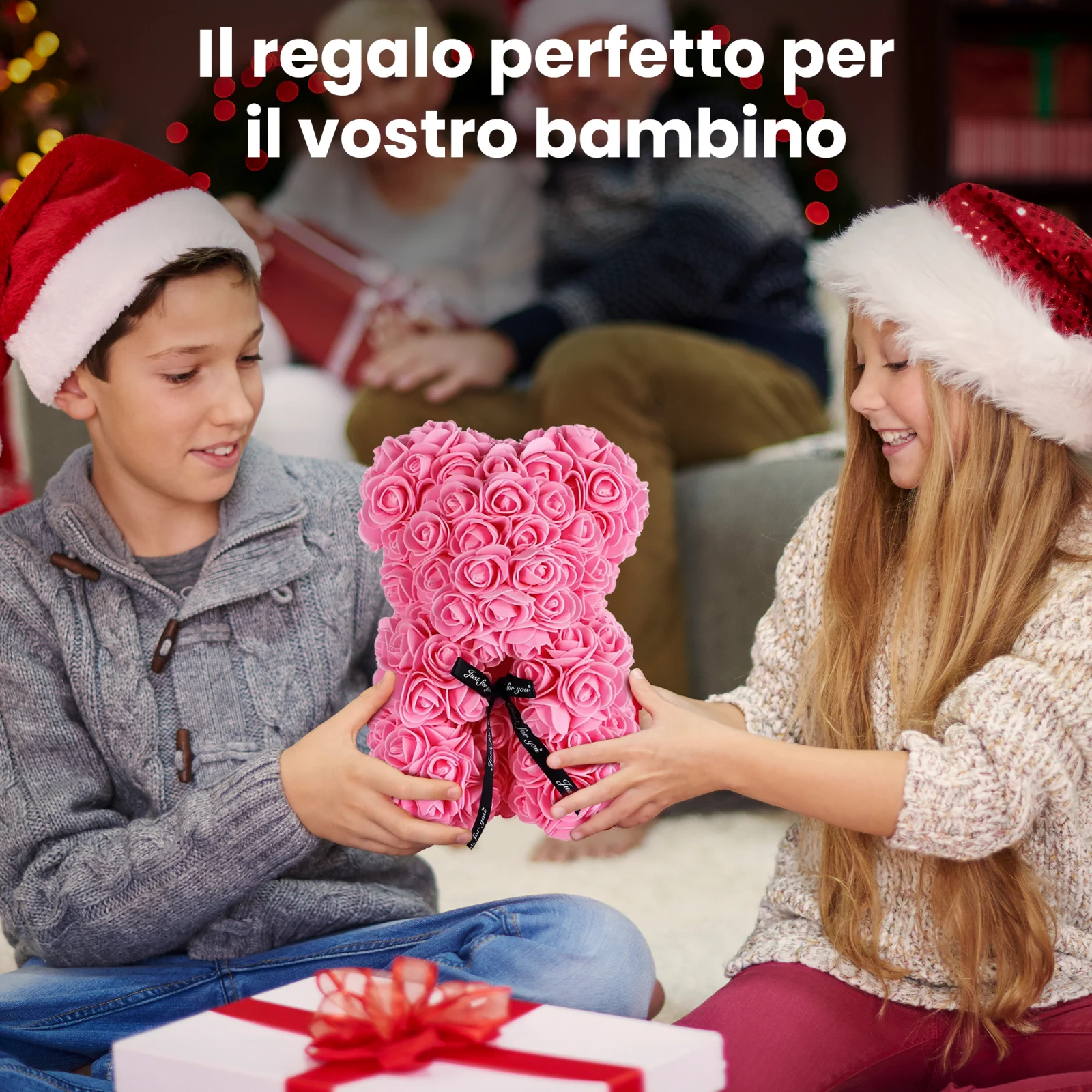 Due bambini sorridenti con cappelli da Babbo Natale, un maschio e una femmina, tengono insieme un orsacchiotto di peluche rosa con