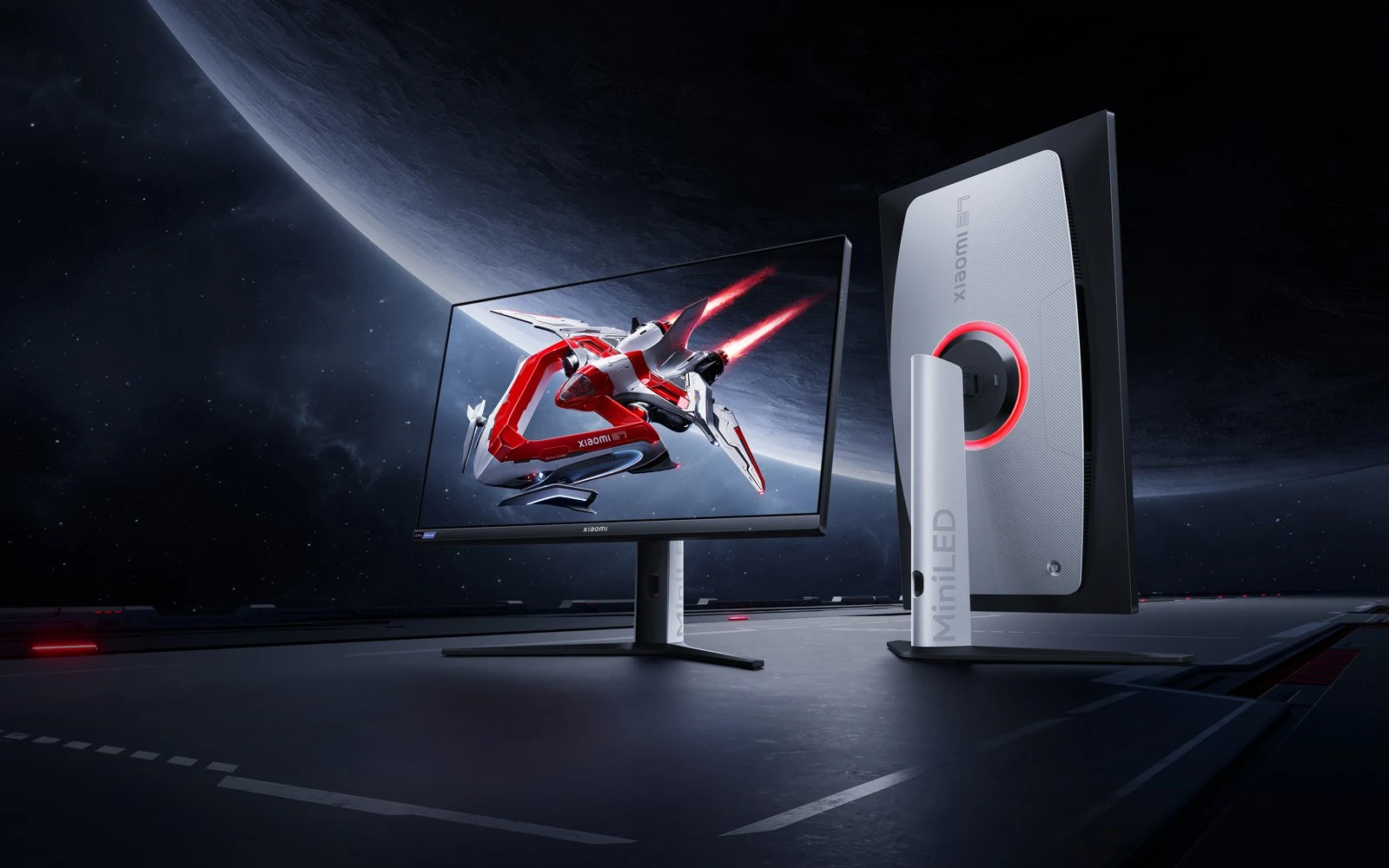 Dois monitores gaming Xiaomi colocados sobre um fundo escuro com gráficos espaciais nos ecrãs