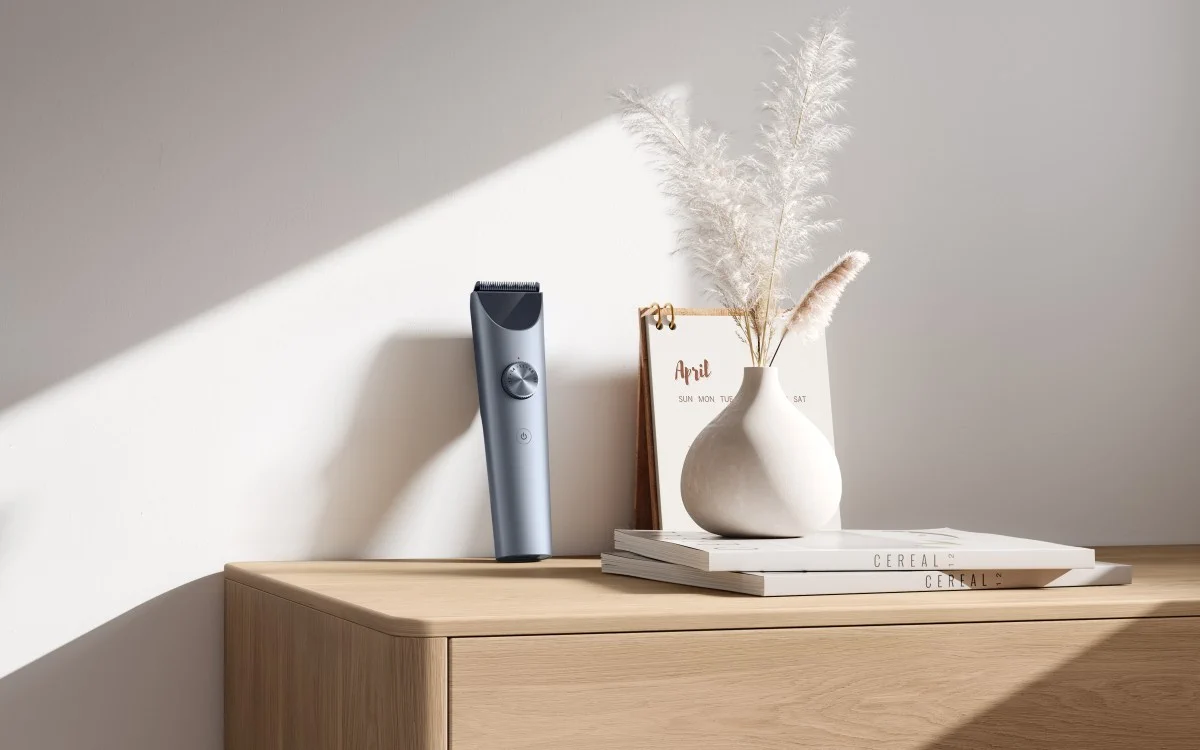 maszynka do strzyżenia xiaomi hair clipper 2 na drewnianej komodzie obok dekoracyjnego wazonu i książek
