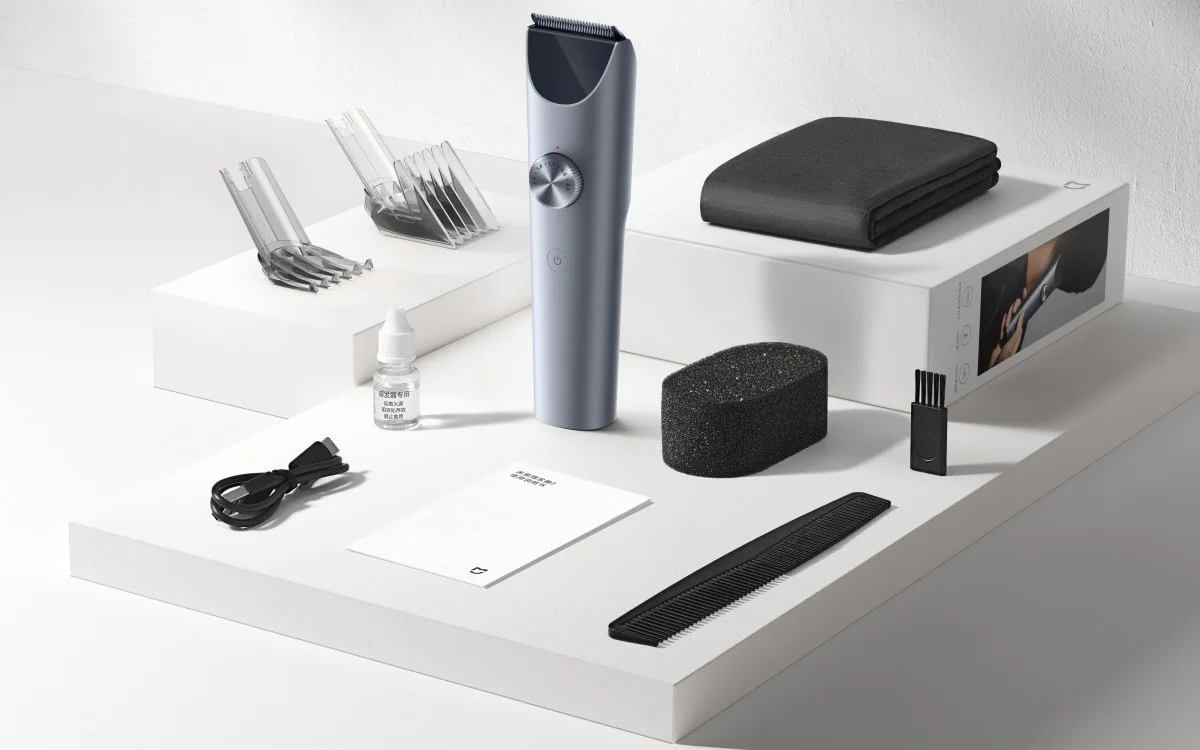 Kompletny zestaw: maszynka do strzyżenia xiaomi, nasadki, grzebień, pędzelek, olej, kabel USB oraz instrukcja, ułożone na białej platformie