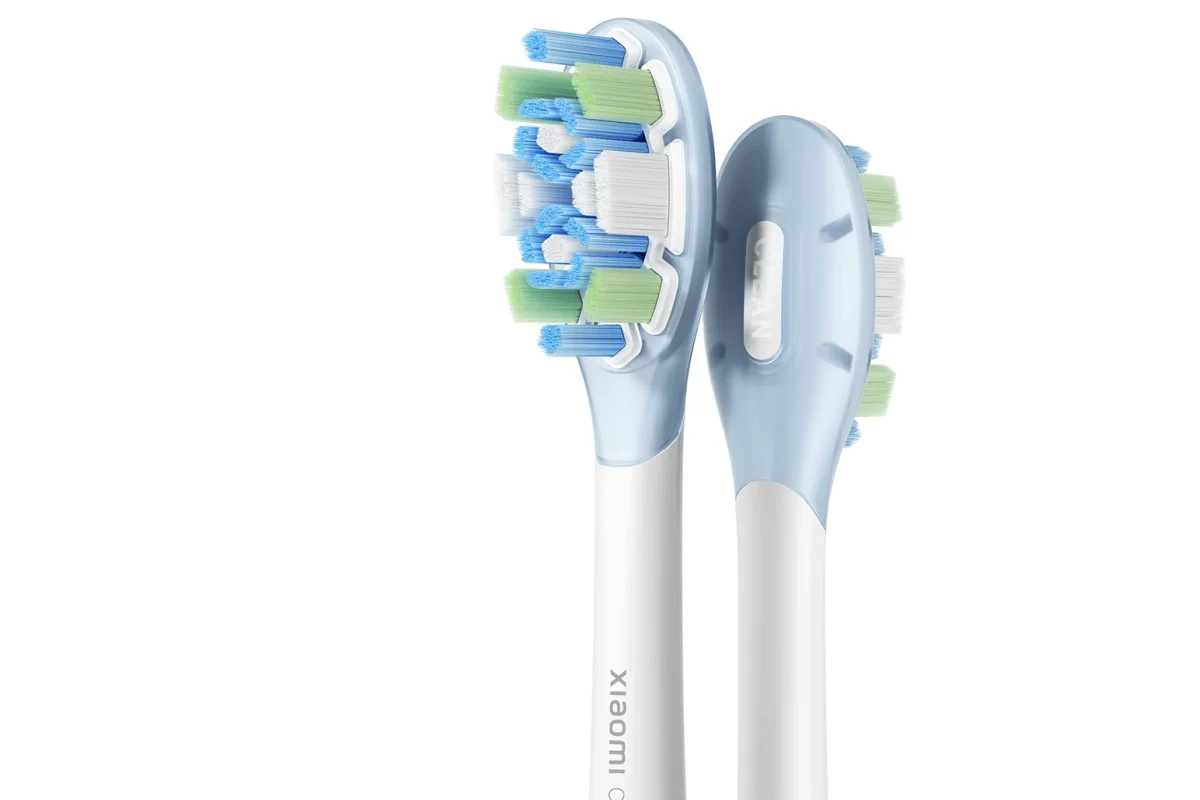 Due testine intercambiabili per spazzolino oscillante con setole blu, verdi e bianche su una base azzurra chiara