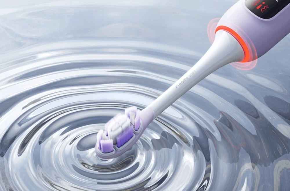 Cabeça da escova tocando a superfície da água, criando círculos concêntricos, com um anel vermelho do sensor visível