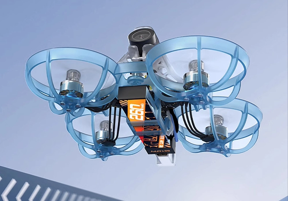 Dron BetaFPV Air65 z widokiem na baterię w kolorze pomarańczowym i niebieskimi osłonami silników. W tle widać jasne niebo