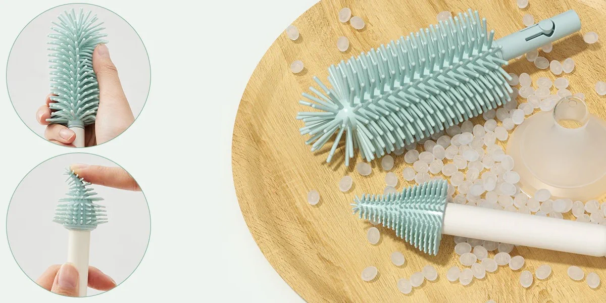 Close-up de escovas de silicone para biberões e chupetas pousadas numa bandeja de madeira ao lado de elementos transparentes