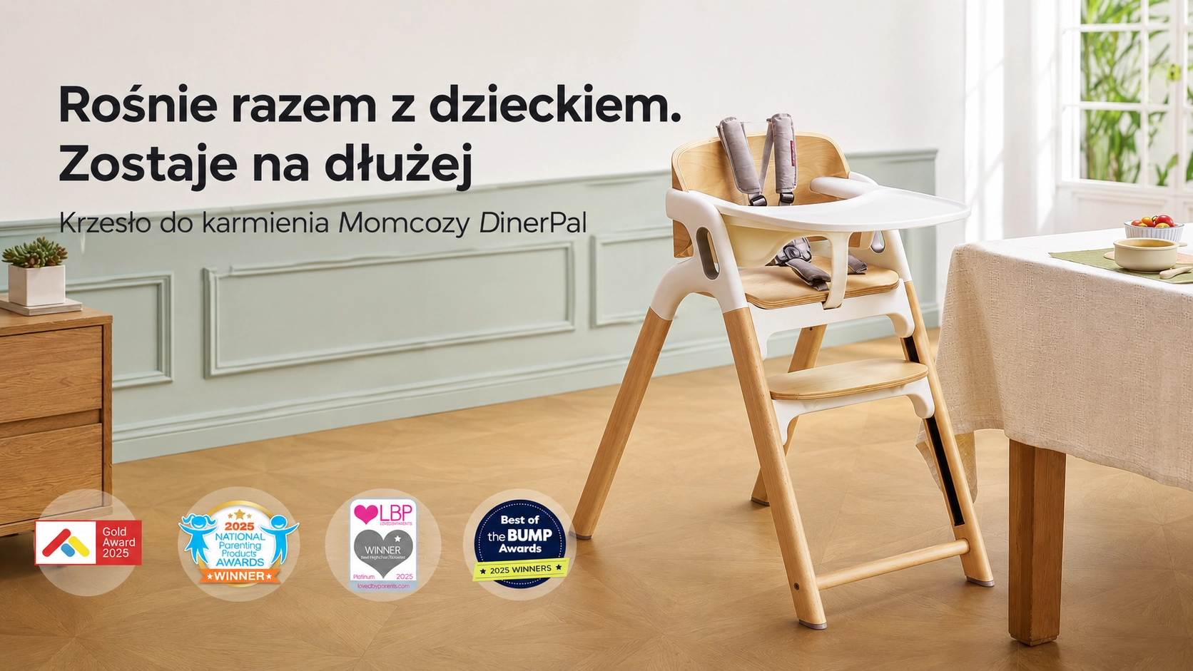 Krzesełko Momcozy DinerPal z białą tacką i pasami bezpieczeństwa stojące obok stołu w jadalni z odznakami nagród