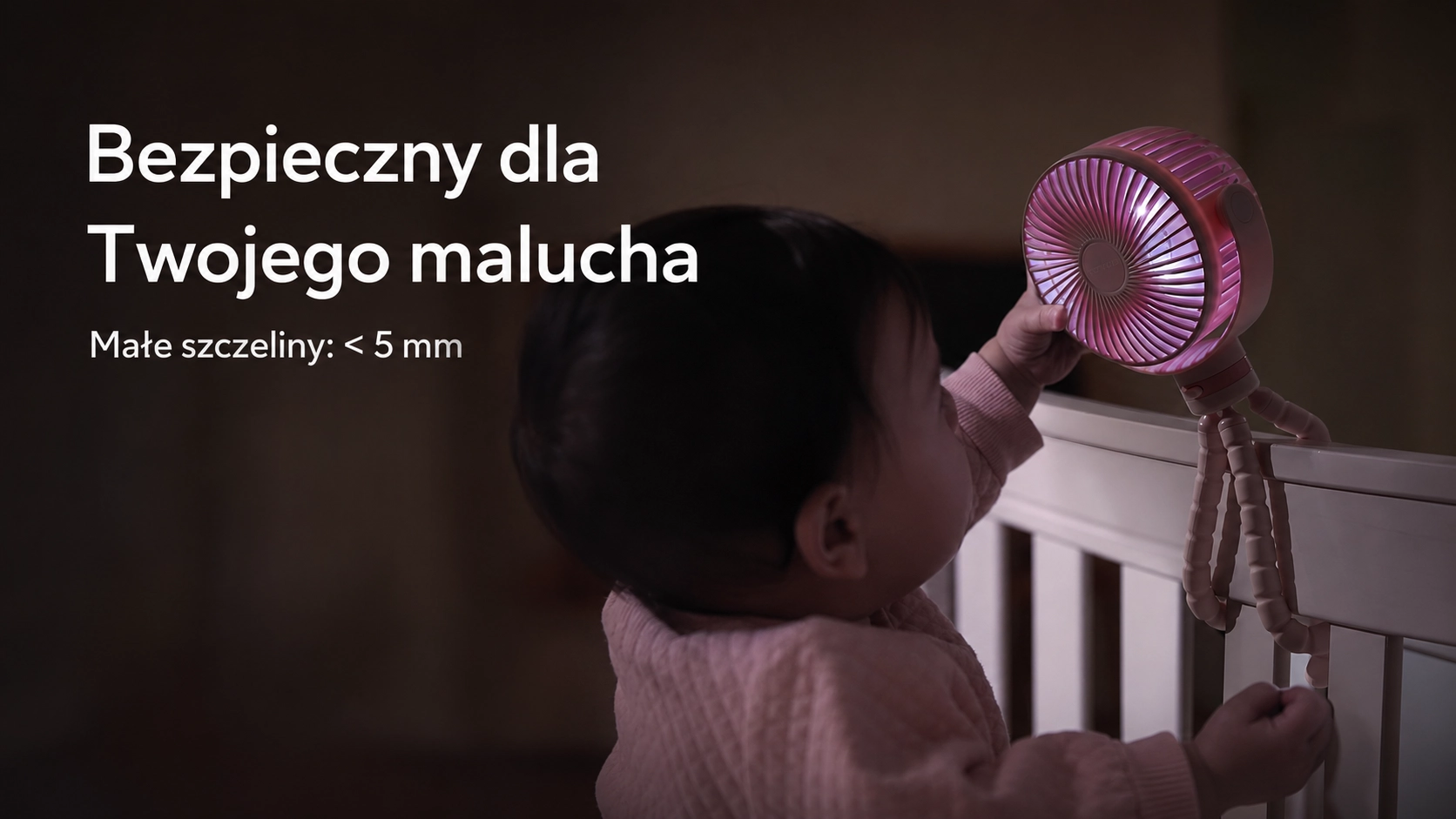 A toddler in a cot reaches for the dense guard of the Momcozy fan with safe gaps below 5 millimetres