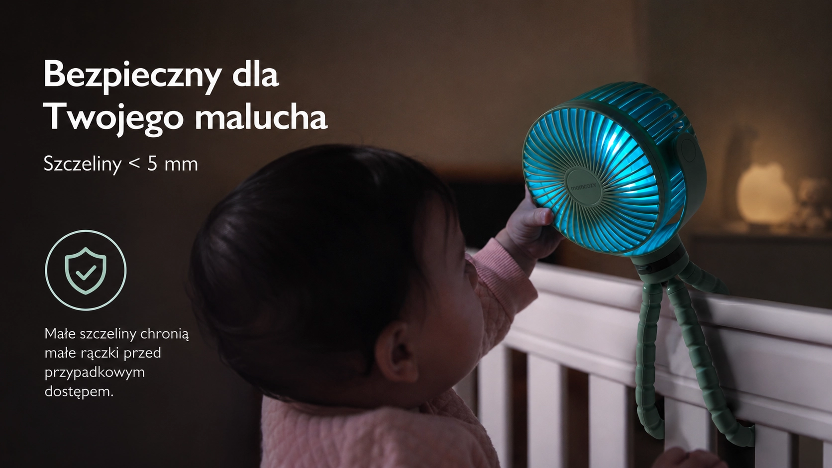 Un bambino nella culla afferra la fitta griglia del ventilatore Momcozy con fessure sicure inferiori a 5 millimetri