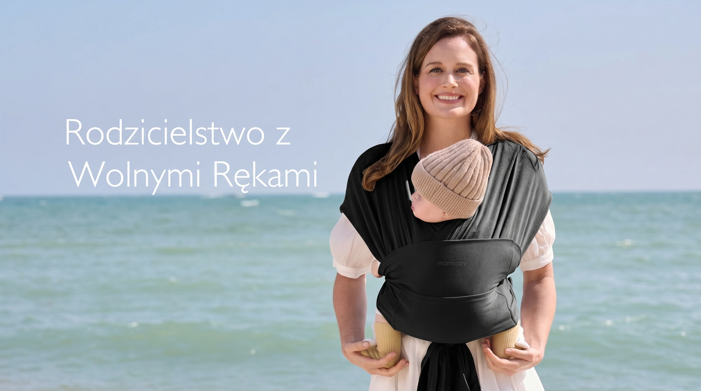 Canguru tipo sling Momcozy M20SSCJ01 Baby Wrap. Mulher sorridente carregando um beb&ecirc; em um canguru el&aacute;stico preto na praia.