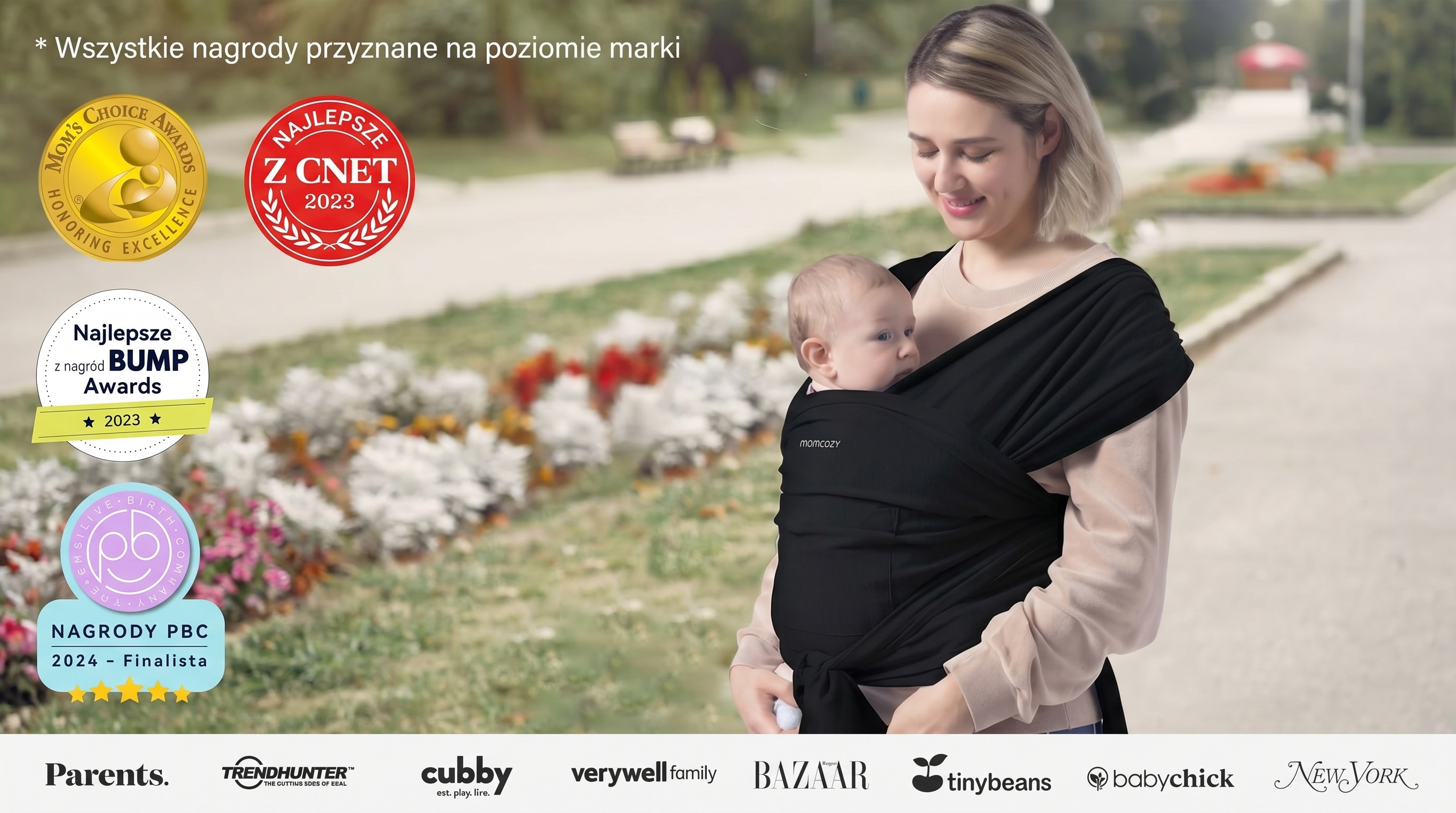 Canguru tipo sling Momcozy M20SSCJ01 Baby Wrap. Mulher com crian&ccedil;a em um canguru preto no parque, ao lado de logotipos de pr&ecirc;mios.