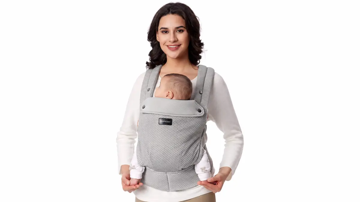 Una donna porta un bambino in un marsupio grigio con un'ampia cintura lombare.