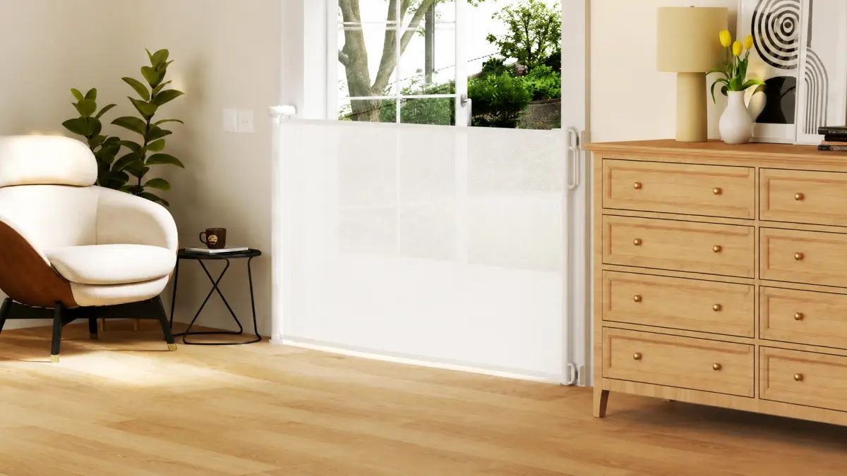 Barrera de seguridad blanca instalada junto a la puerta del patio en un sal&oacute;n moderno, junto a un sill&oacute;n y un mueble.