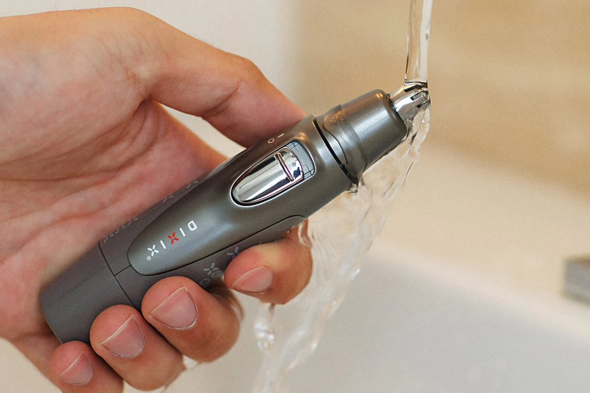 un hombre enjuaga el cabezal de la recortadora dix bajo el grifo