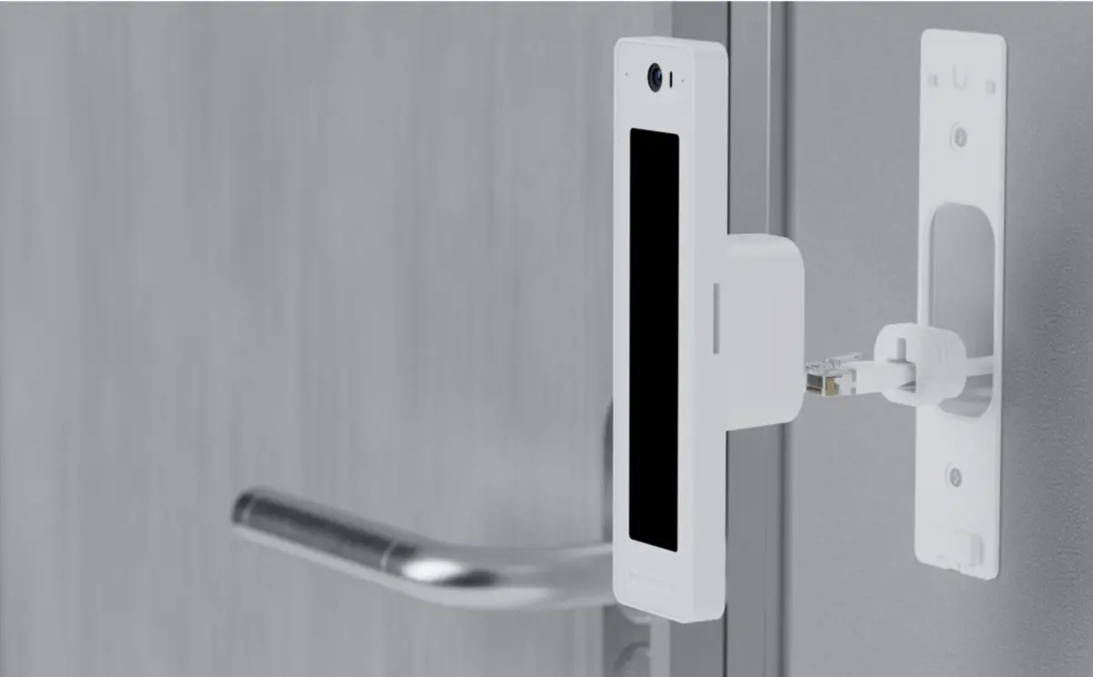 Sistema de acceso a la puerta durante la instalación, mostrando la conexión del dispositivo al mecanismo de cierre de la puerta mediante un cable.