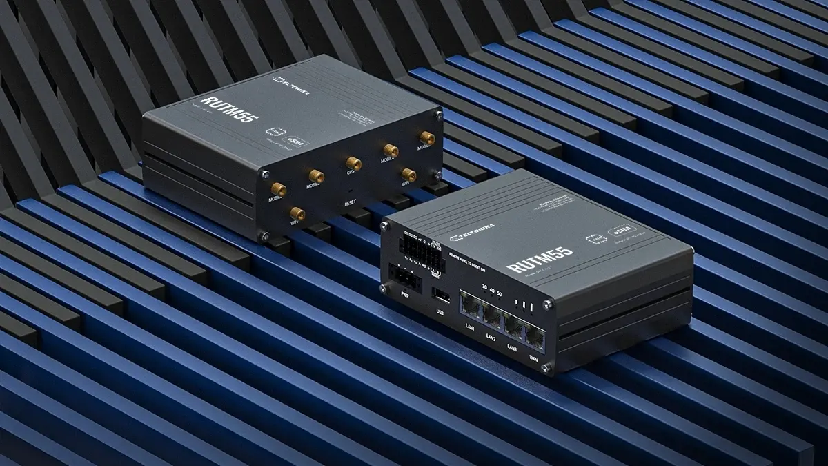 Dois routers Teltonika RUTM55 lado a lado, vista vis&iacute;vel da parte frontal dos dispositivos com portas e antenas, posicionadas contra as barras azuis.