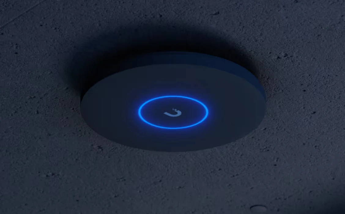 A round access point on the ceiling, with a blue-lit ring.