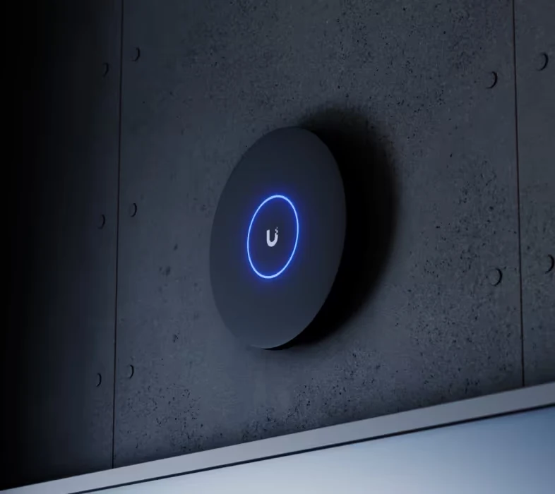 Ubiquiti access point with a lit ring, shown during wall mounting.