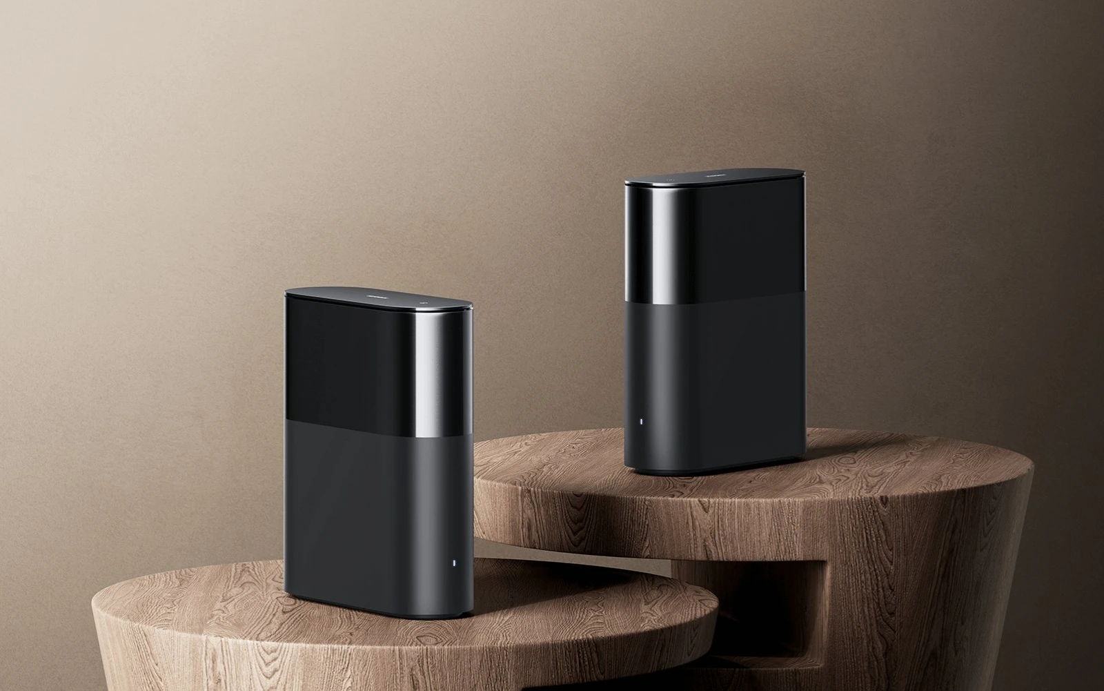 Dois roteadores pretos do sistema Xiaomi Mesh colocados sobre mesas redondas de madeira em fundo bege