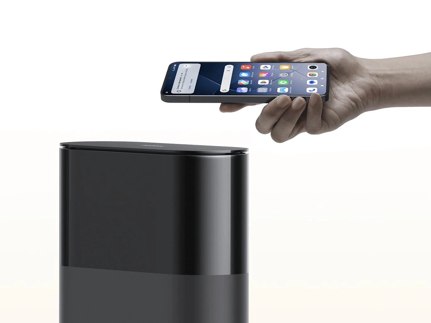 Uma m&atilde;o aproximando um smartphone da parte superior de um roteador preto para pareamento r&aacute;pido de dispositivos