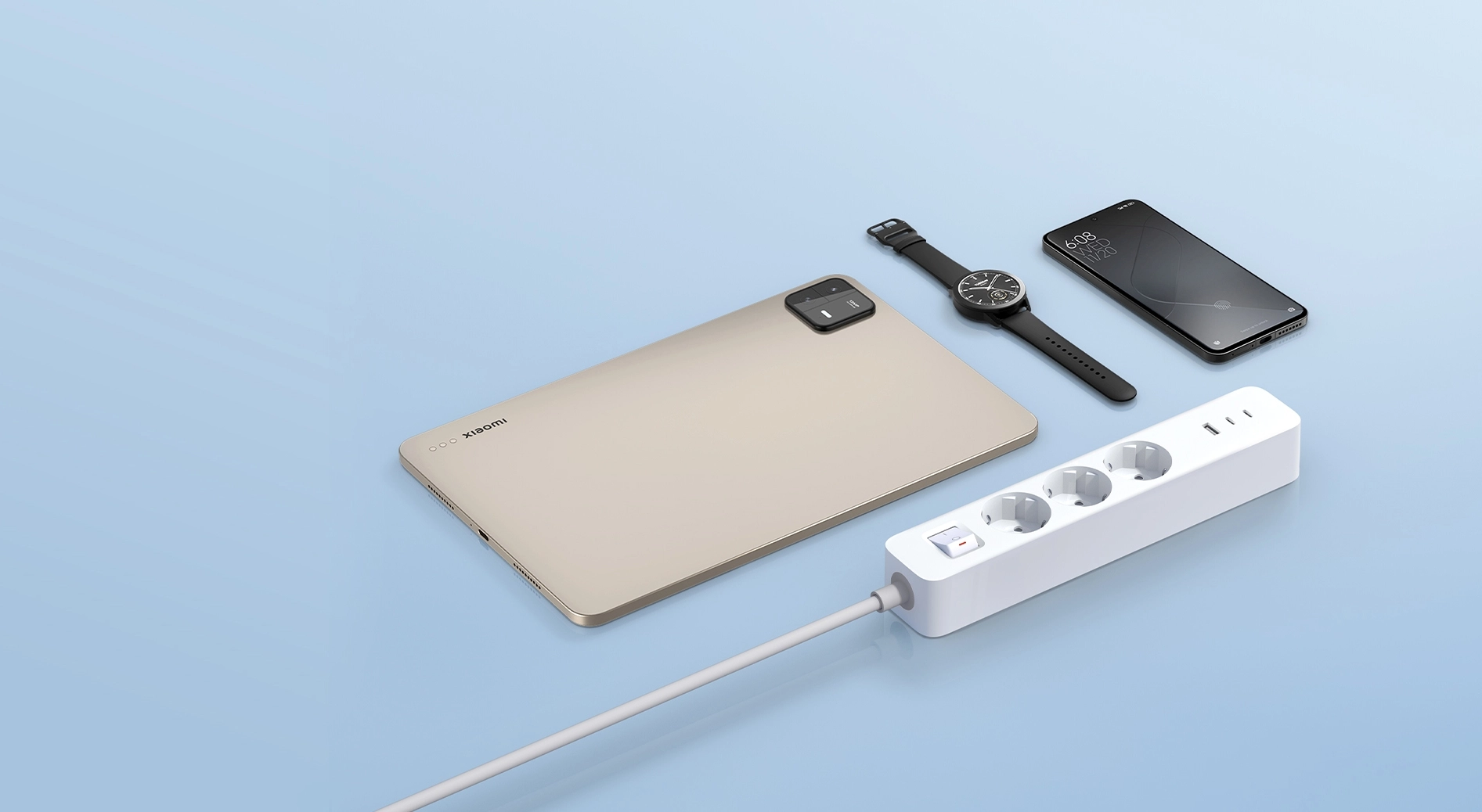 Listwa zasilająca Xiaomi Power Strip 20W z trzema gniazdami, portami USB oraz przyciskiem włączania, obok telefon, tablet i smartwatch na tle niebieskiego tła