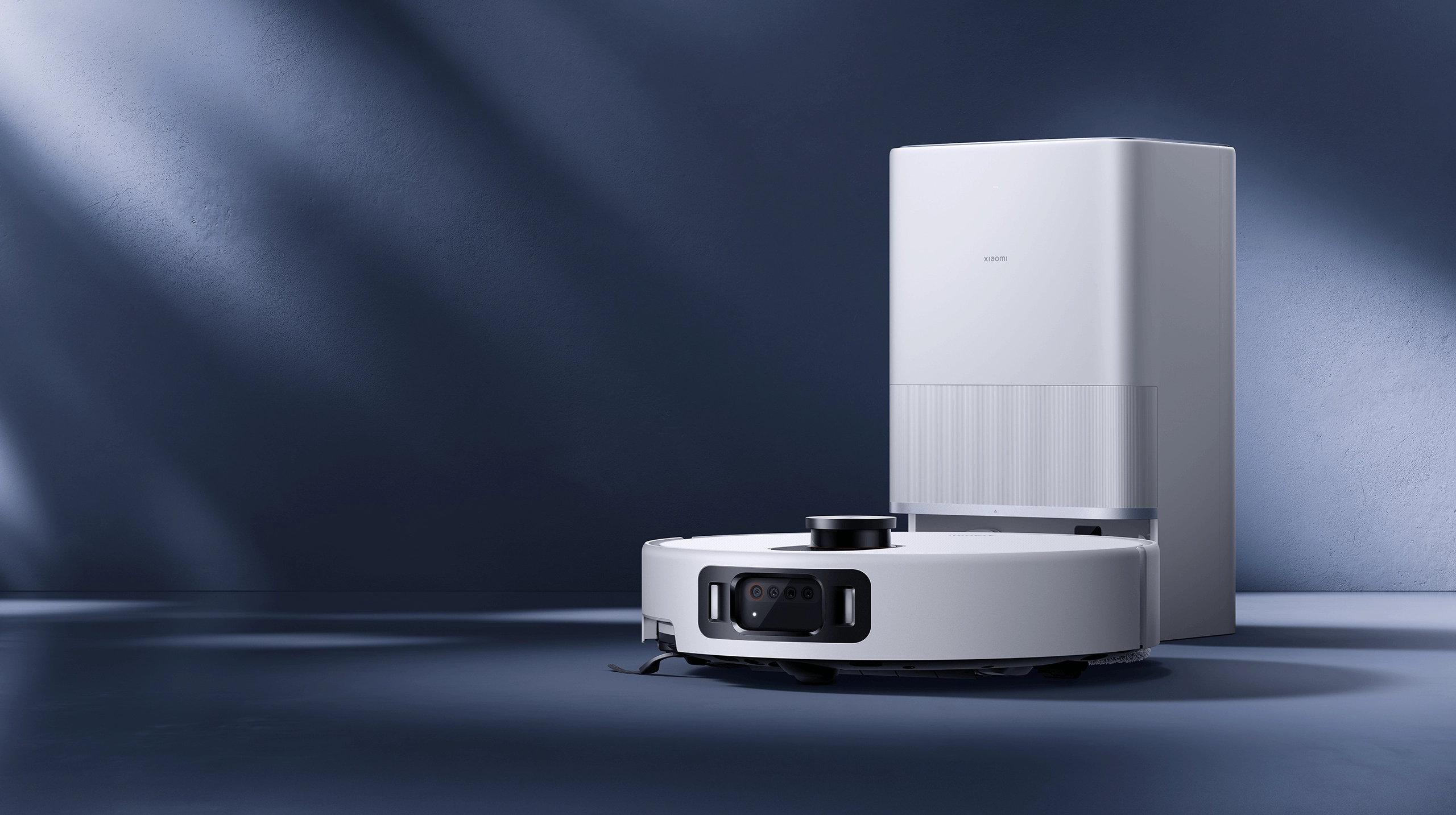 Xiaomi Robot Vacuum 5 Pro стоит рядом с зарядной станцией на фоне минималистичного интерьера с синей стеной