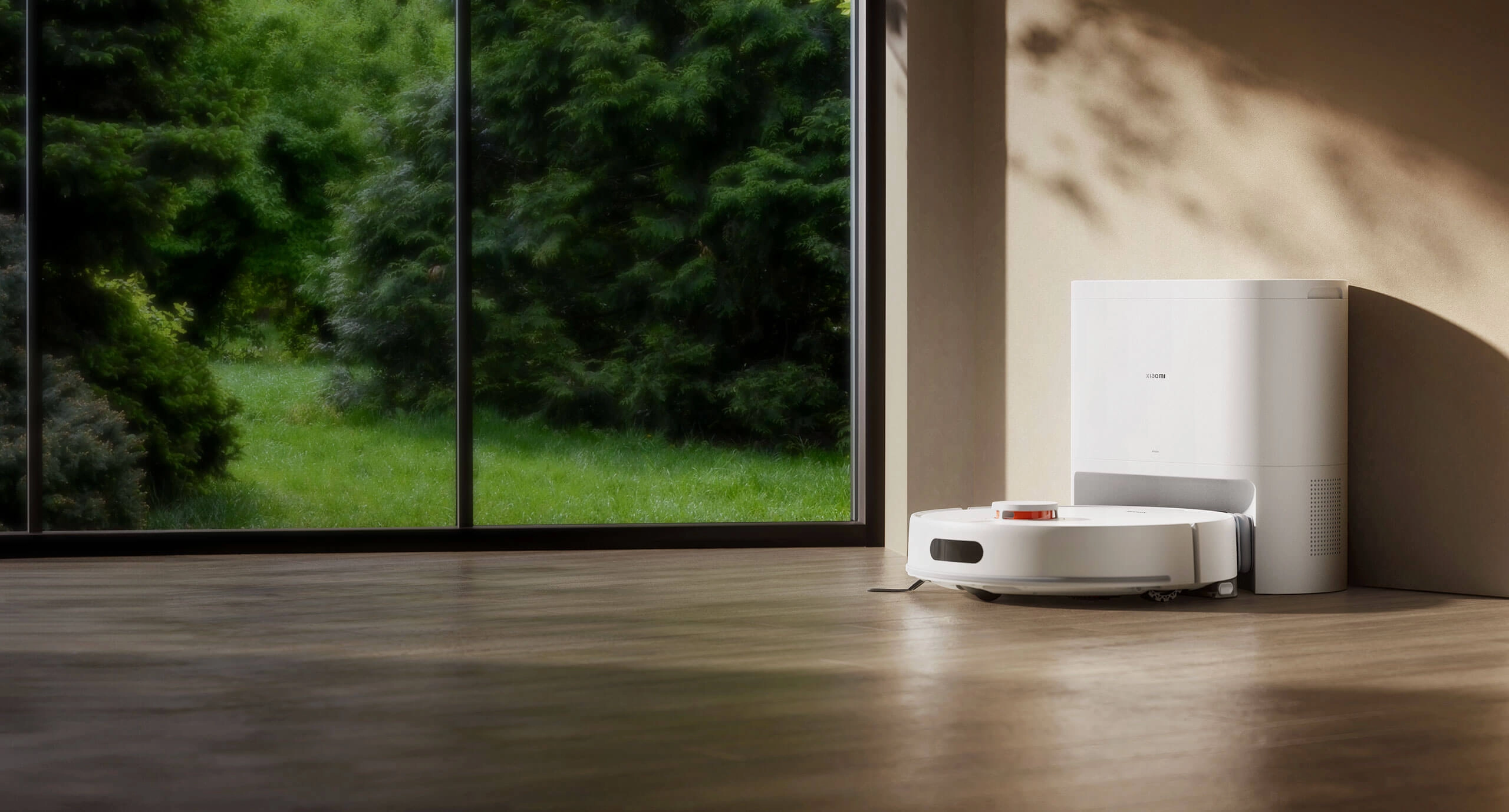 Робот-пылесос Xiaomi H40 стоит на деревянном полу рядом с зарядной станцией, с видом через большое окно на улицу