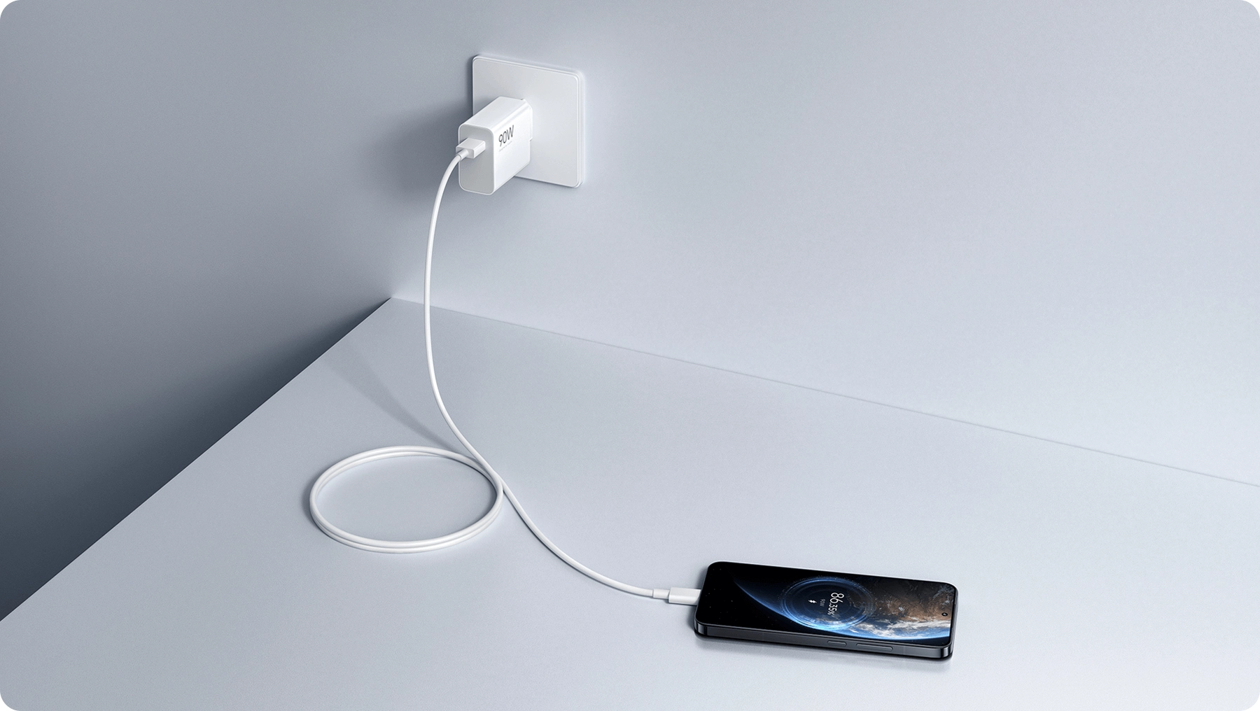Ładowarka Xiaomi 90W HyperCharge Combo EU podłączona do gniazdka, z przewodem prowadzącym do smartfona ładowanego na blacie stołu