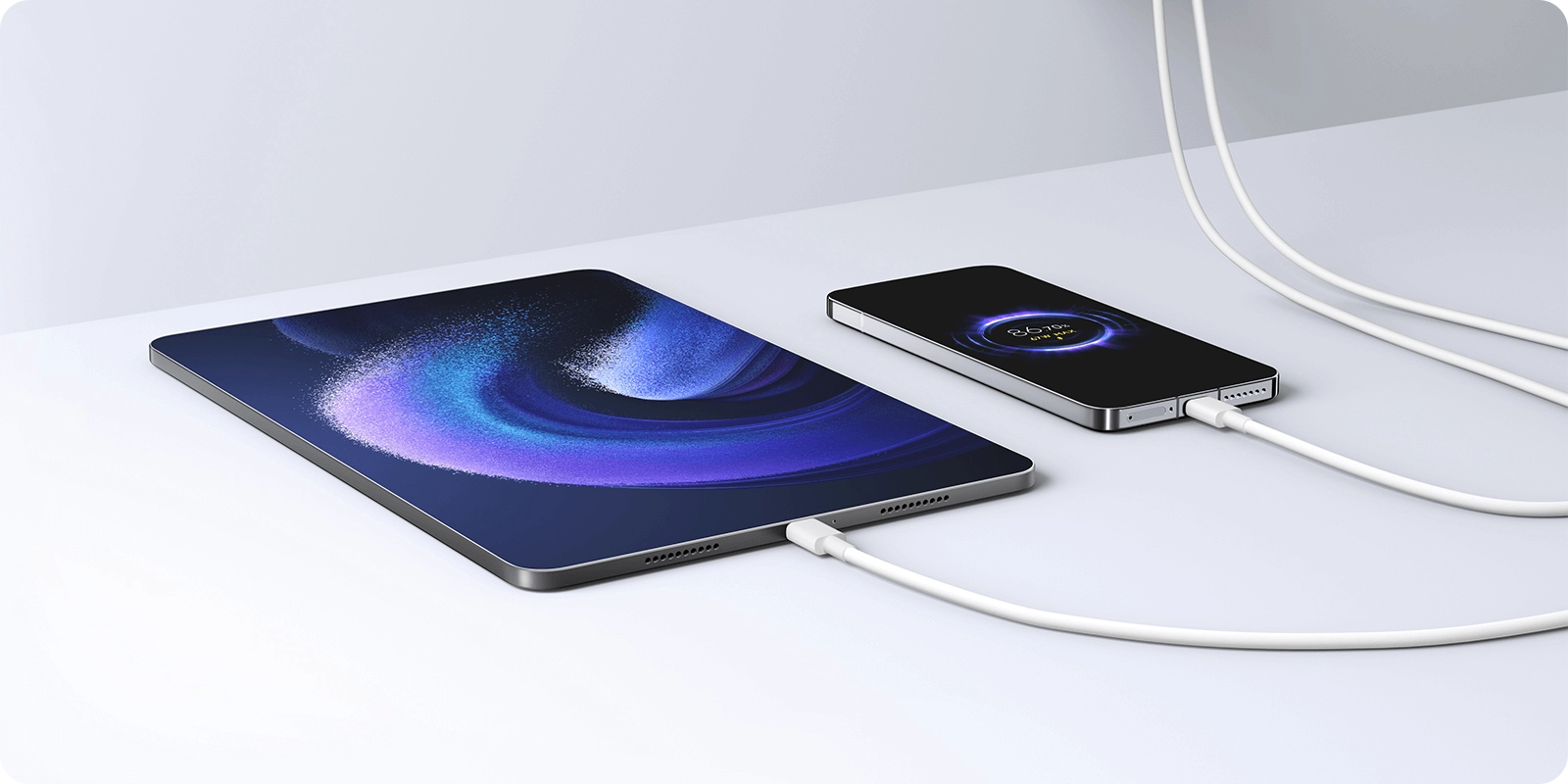 Telefon i tablet ładowane jednocześnie za pomocą ładowarki 90W, na tle białej powierzchni