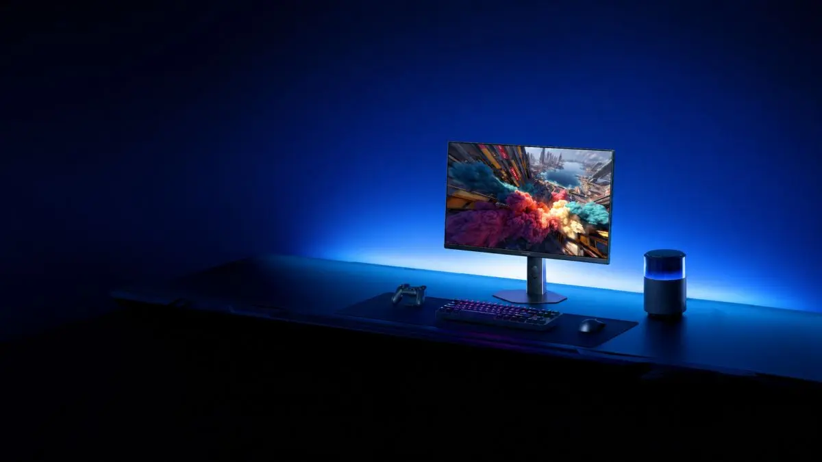 Monitor gaming numa secretária com teclado, rato, comando e altifalante iluminado.