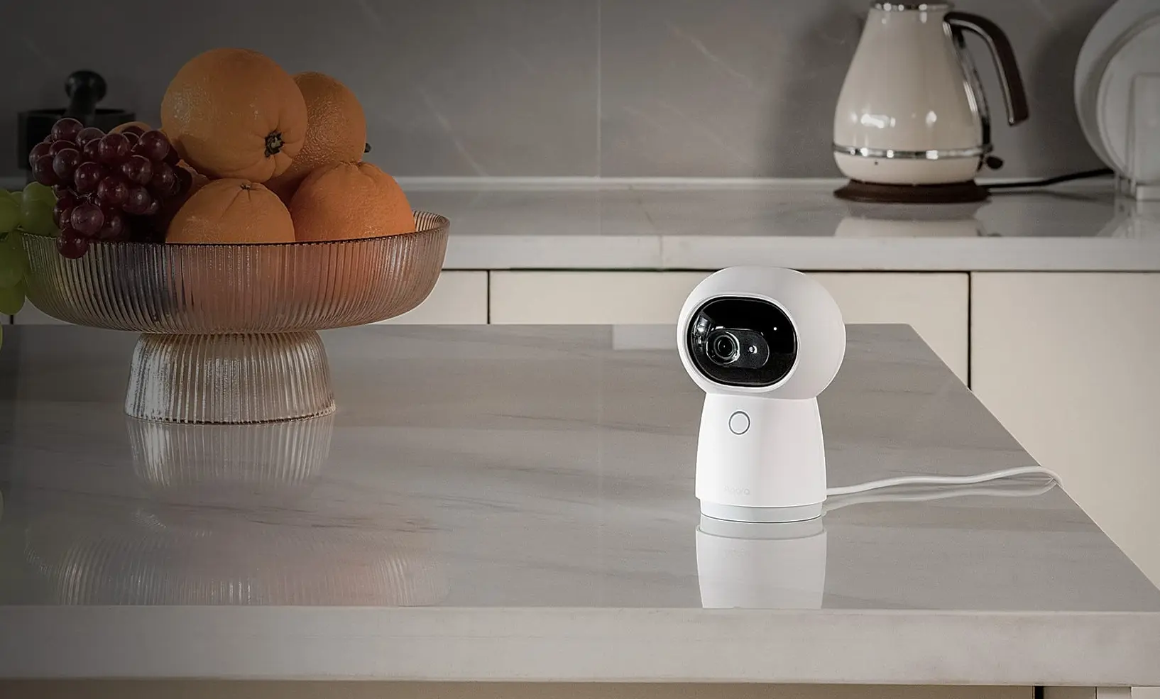 Kamera Aqara na tle owoców w kuchni, monitorująca przestrzeń