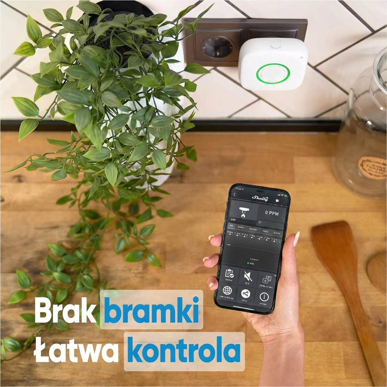 Czujnik gazu Shelly w gniazdku, z widoczna aplikacją na telefonie do łatwego monitorowania gazu, z rośliną w tle
