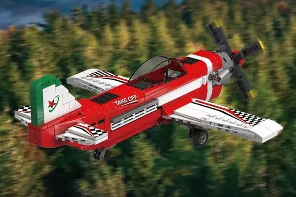 Vista traseira de um avião de brinquedo de blocos em voo. Fuselagem vermelha, asas brancas e detalhes nas cores da bandeira