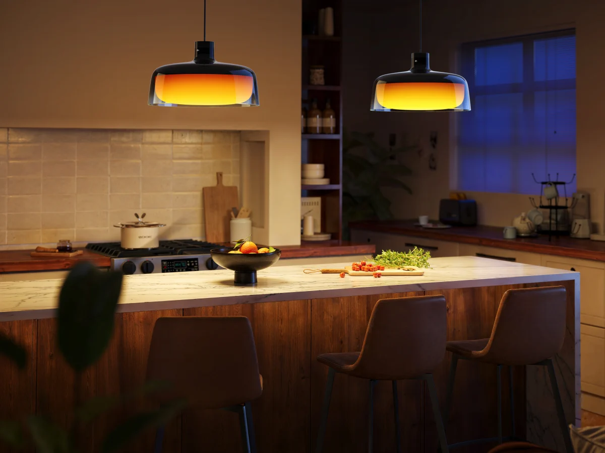 Two H60C1 pendant lights with orange light above a kitchen island in a cosy interior