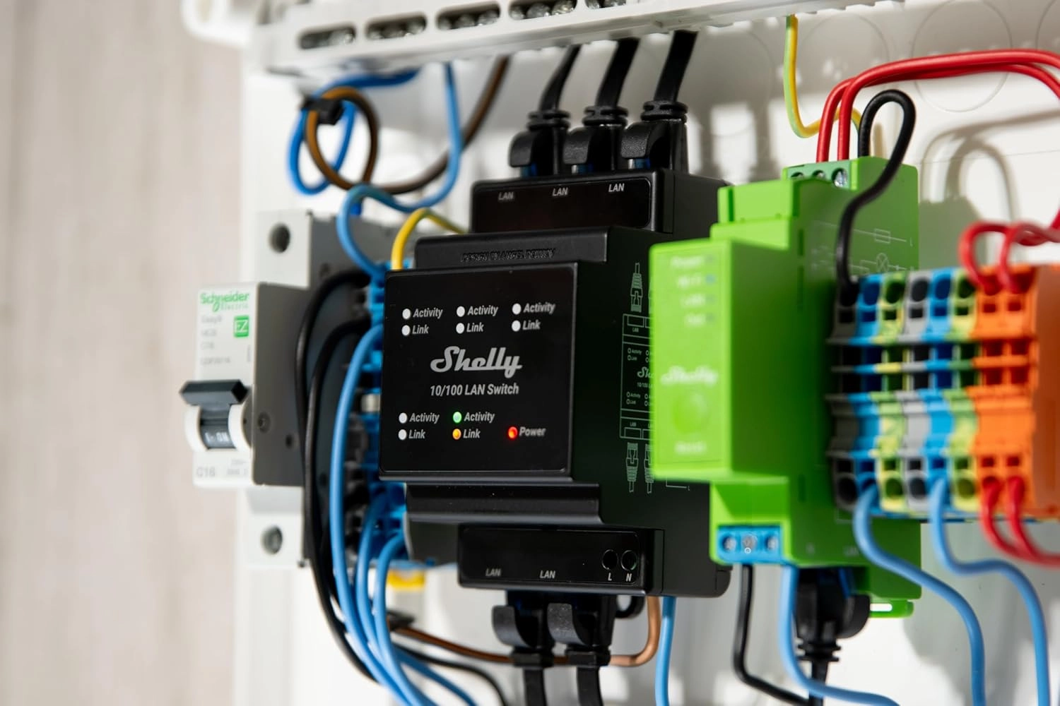 Zbliżenie przełącznika LAN Shelly w szafce, z widocznymi portami LAN, diodami LED oraz przewodami elektrycznymi