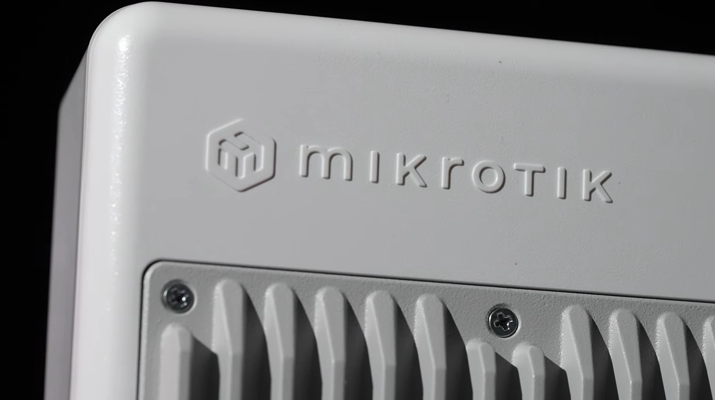 Na obudowie Mikrotik NetPower Lite 8P widoczny jest detal z logiem firmy oraz żeberkami chłodzenia