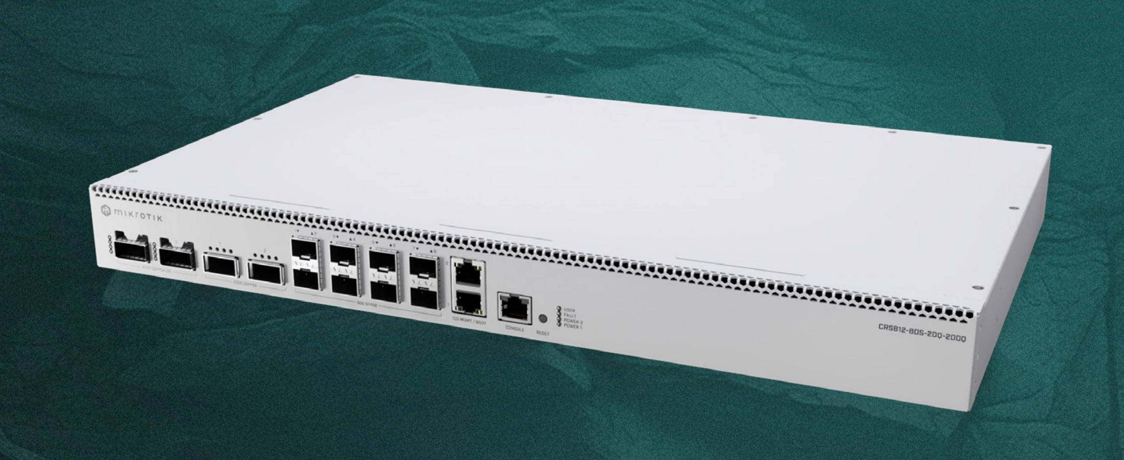 MikroTik CRS812-8DS-2DQ-2DDQ-RM pokazany z przodu, biały metalowy switch na zielonkawym tle, widoczne porty sieciowe