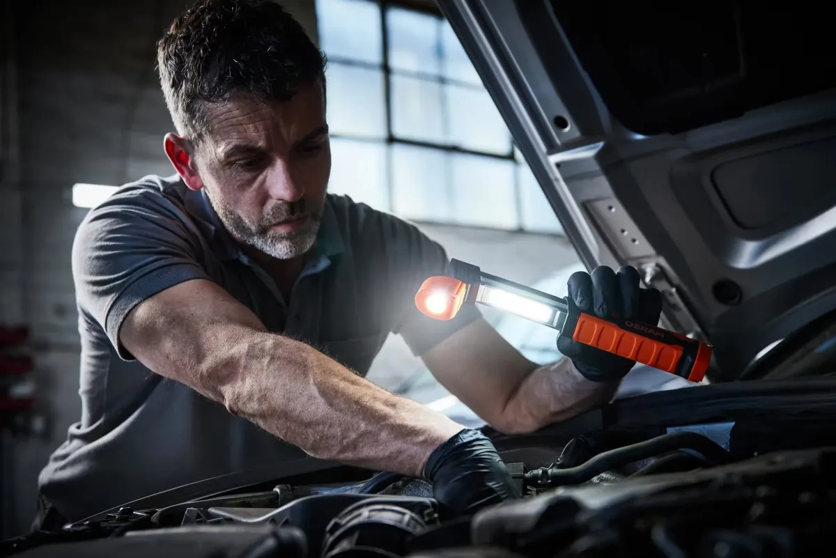 Mechanik trzyma wysuniętą lampę teleskopową OSRAM, kierując jasny strumień światła na podzespoły silnika.