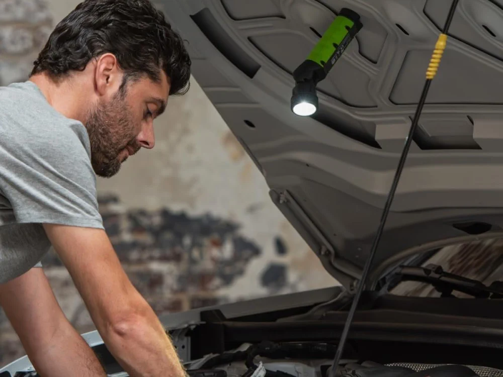 Mechanik pracujący przy otwartej masce samochodu korzysta z latarki zamocowanej magnetycznie nad silnikiem